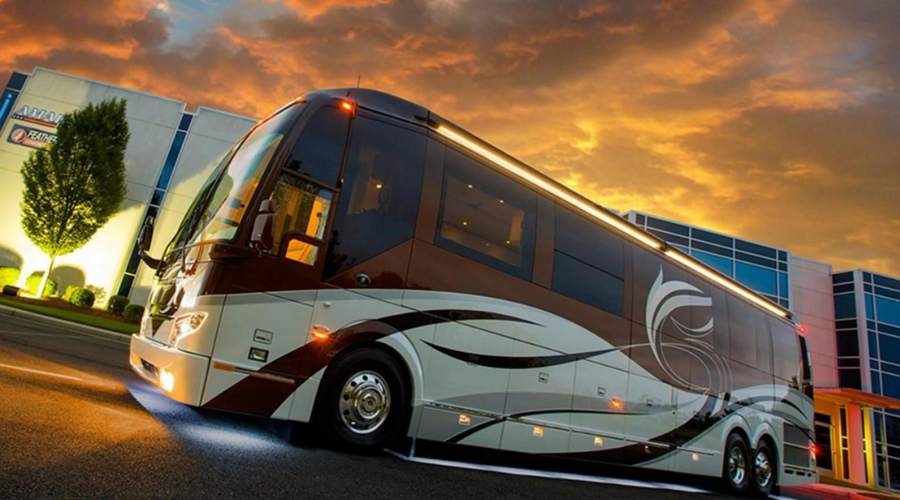 Luxury charter bus parked on a street at sunset.